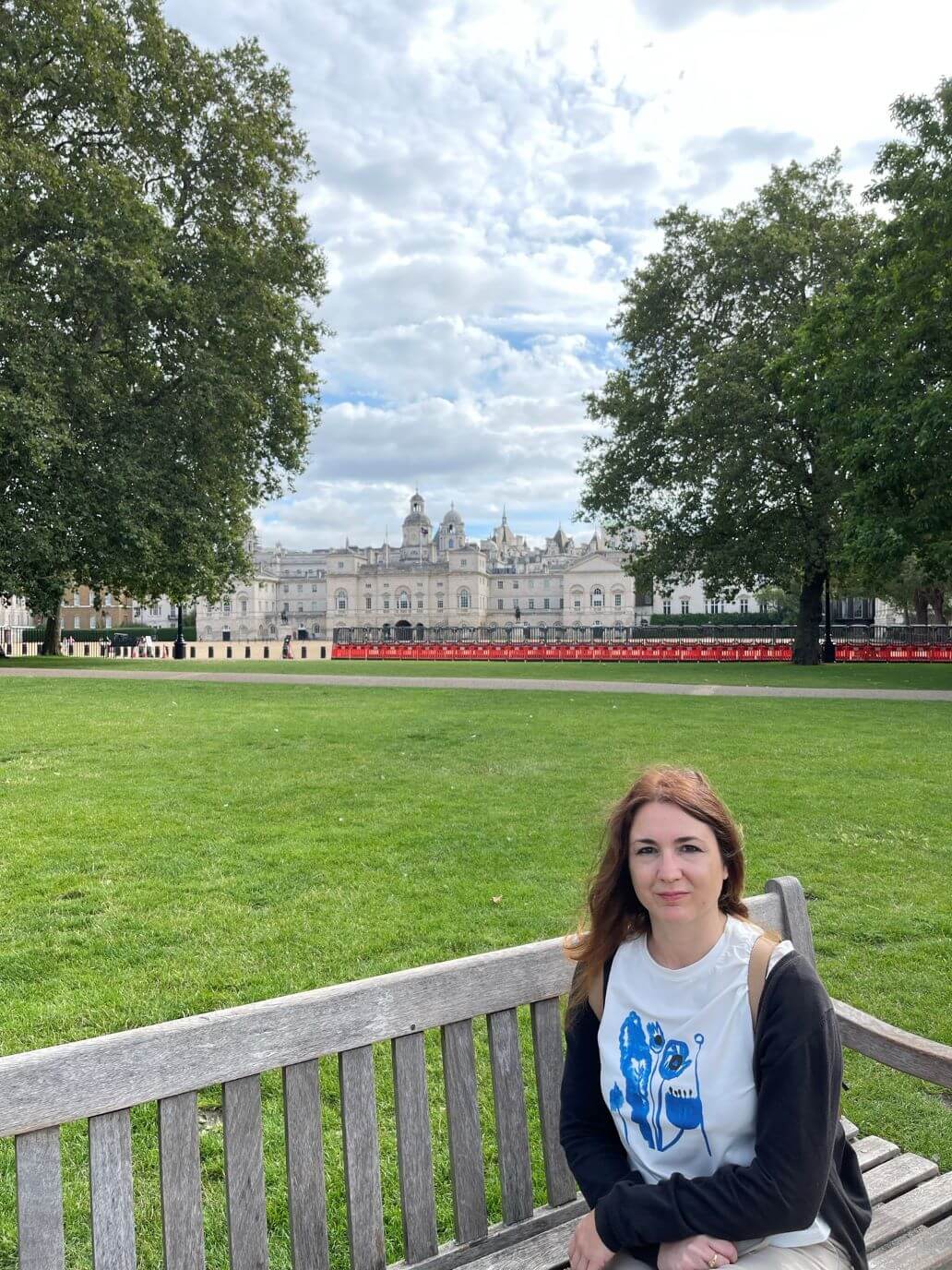 chiara di viaggi e ritratti seduta su una panchina a st james park con alle spalle buckingham palace