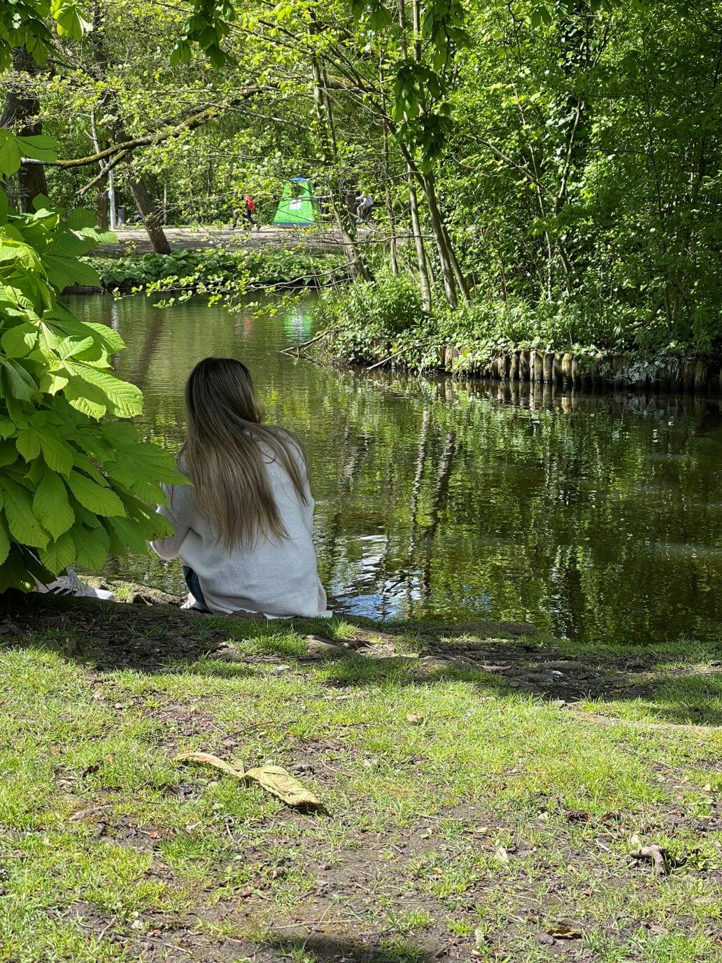 una ragazza seduta sul prato del vondelpark